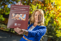 Bonnie holds up the printed Caregiver resource.