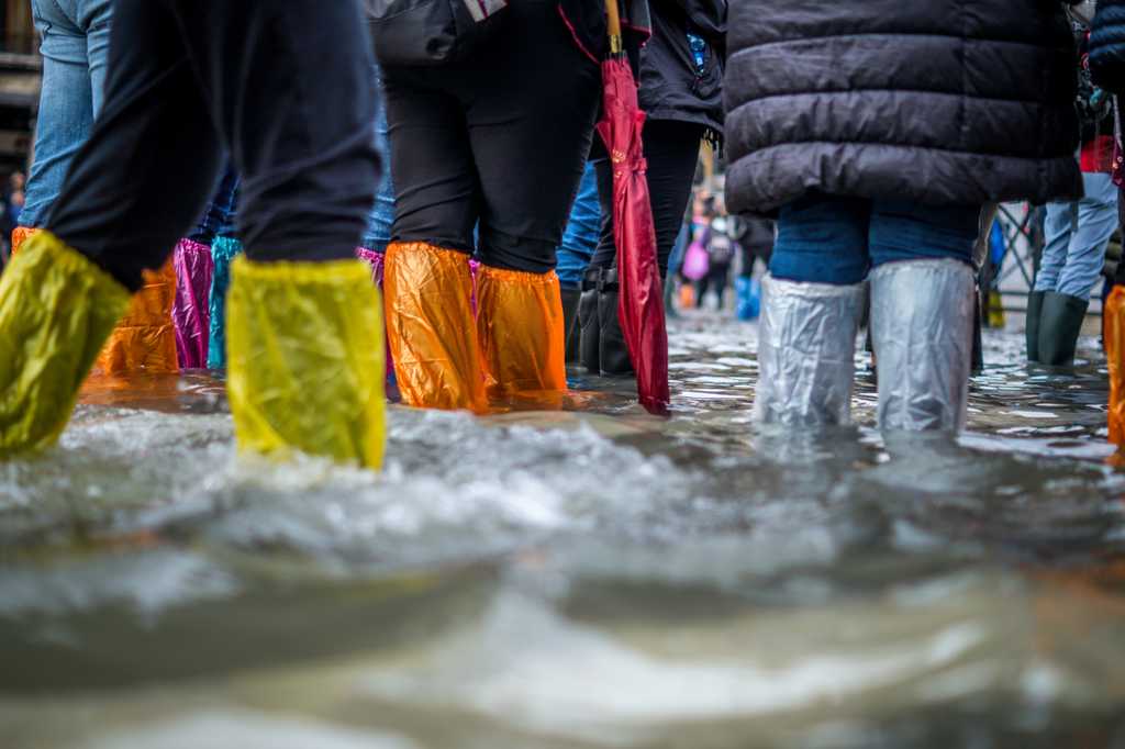 people standing in a flood wearing plastic to protect their legs