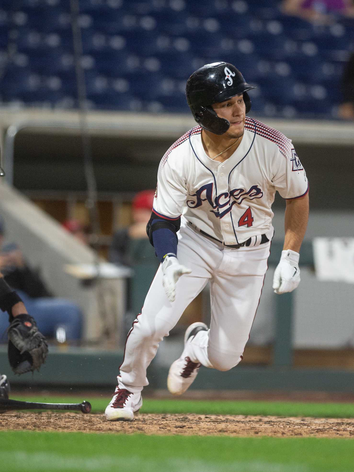 Reno Aces outfielder Alek Thomas running bases at a game, wearing a white  uniform with red number 4 and a blue batting helmet