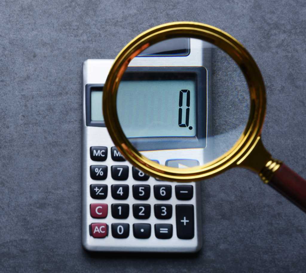magnifying glass magnifying the numeral zero on a small calculator