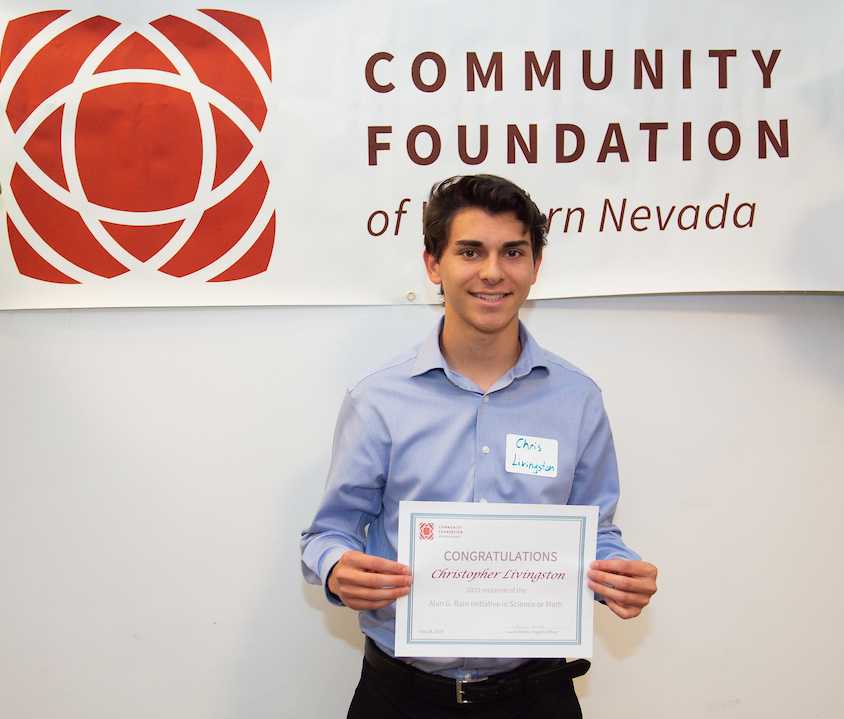 Christopher Livingston, a 2019 student scholarship recipient, stands with his certificate in front of our banner
