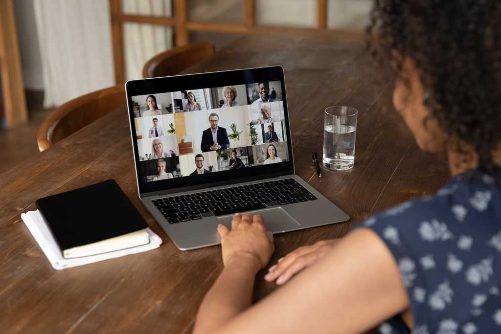 Looking over the shoulder of an adult women viewing her laptop with a virtual meeting going on.