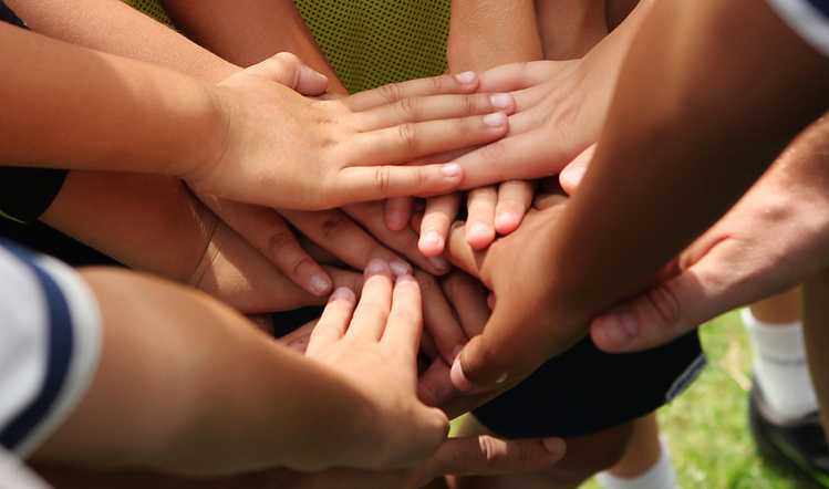 young people pile their hands together in unity