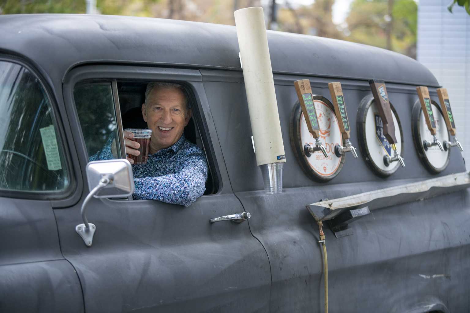 Chris Askin at wheel posing with beer of beer tap vehicle