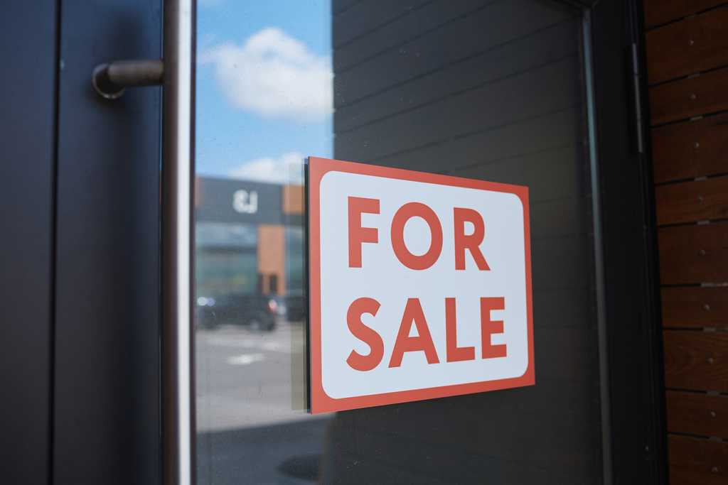 A for sale sign on the glass front door of a business.